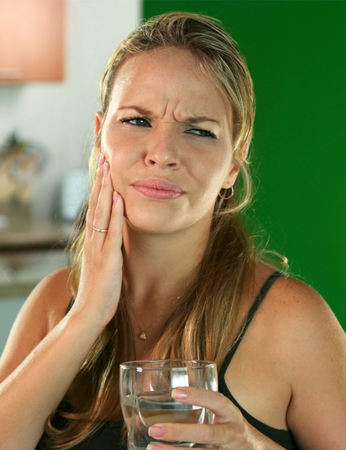 Woman in need of emergency dentistry holding cheek in pain