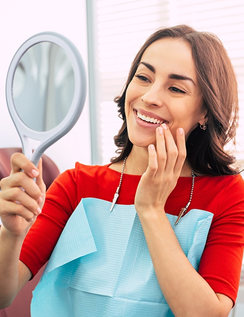 Woman looking at her smile after state of the art dentistry treatment