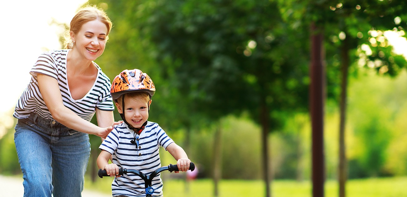 Mother teaching son to ride bike after children's dentistry visit