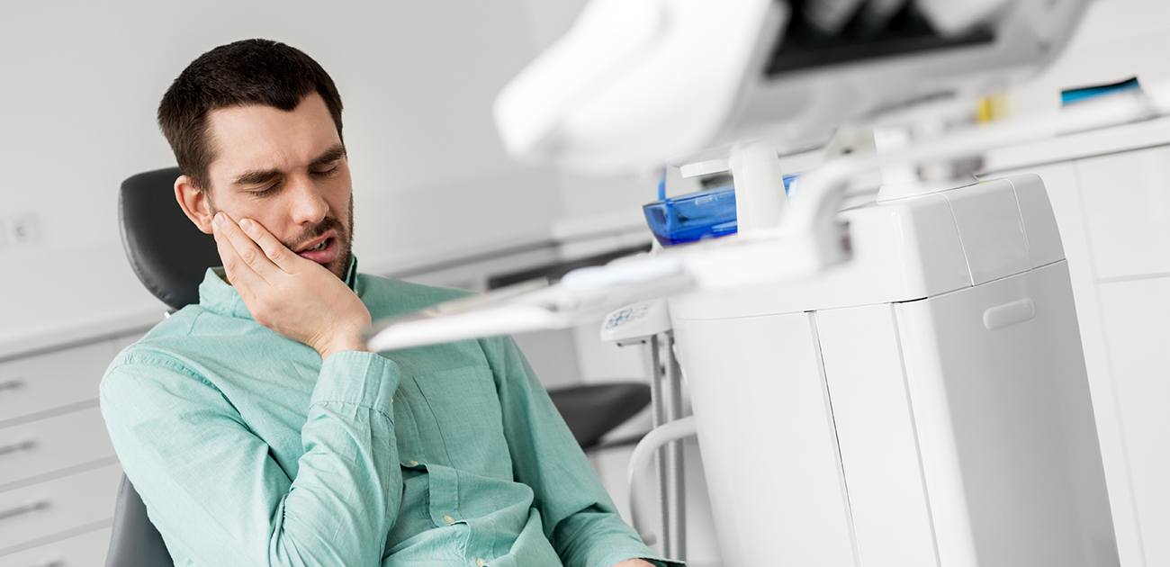 Man in need of sedation dentistry holding jaw in pain