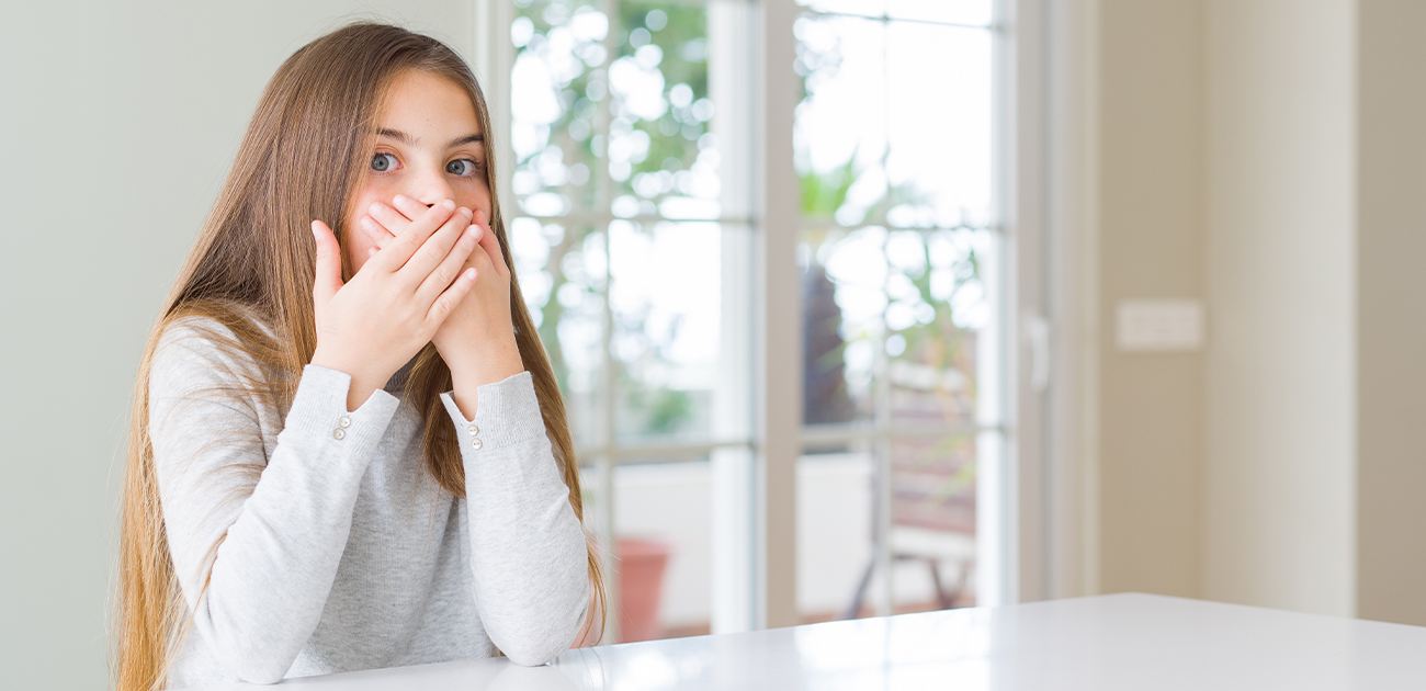 Child in need of sedation dentistry covering her mouth