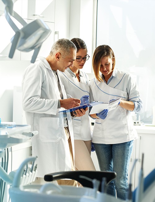 Three dentists reviewing dental patient chart