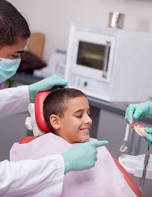 A dentist and dental assistant showing a young boy how to properly brush his teeth