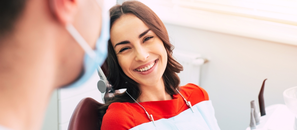 Dentist talking to laughing woman in dental chair