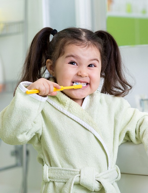 young girl brushing teeth in bathroom 