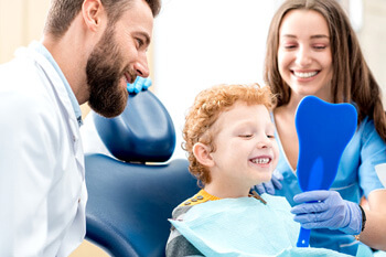 child smiling in mirror after dental treatment