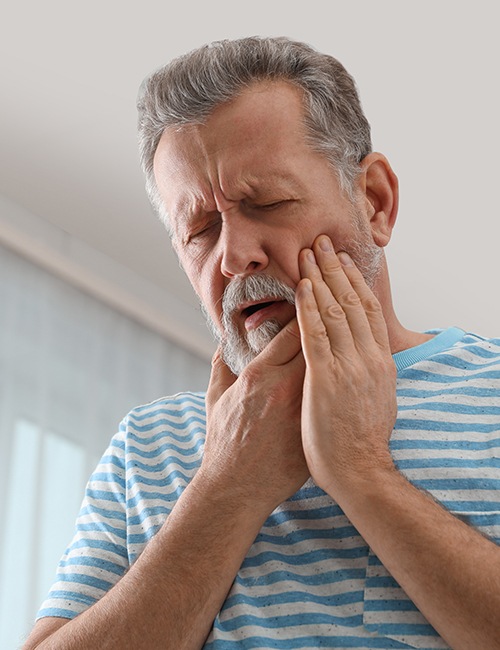 Man in need of tooth extraction holding his cheek