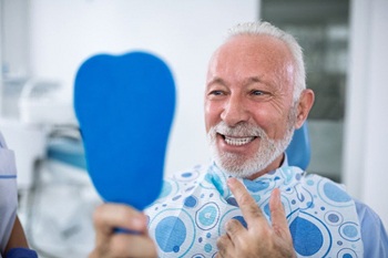 senior man admiring his new smile with dental implants