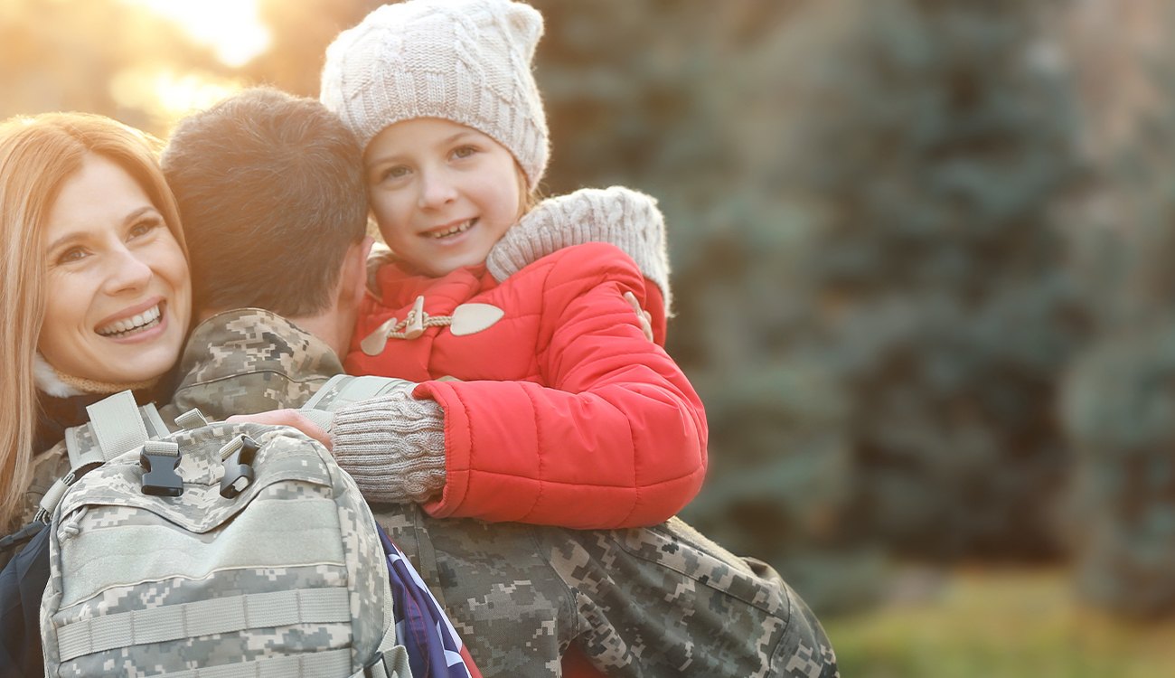 Military service member hugging his wife and child