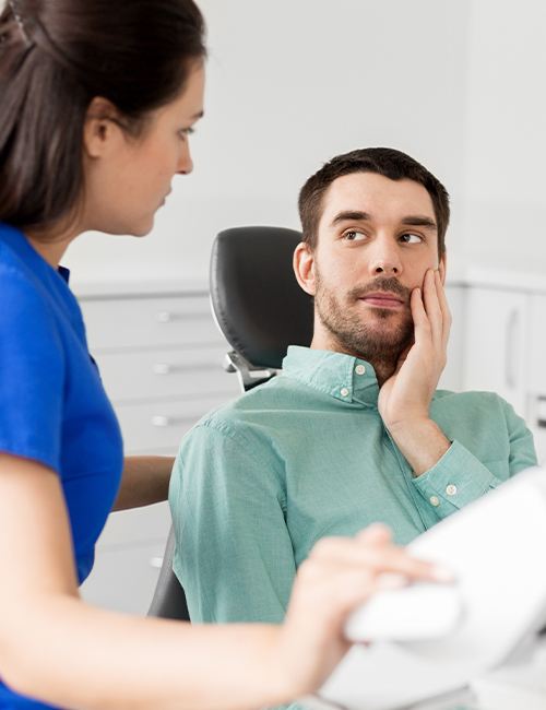 Man in need of root canal holding cheek in pain