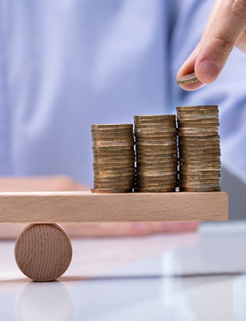 Tooth and stacks of coins on wooden balance