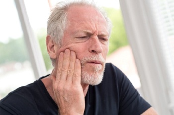 Older man holding jaw in pain on white background