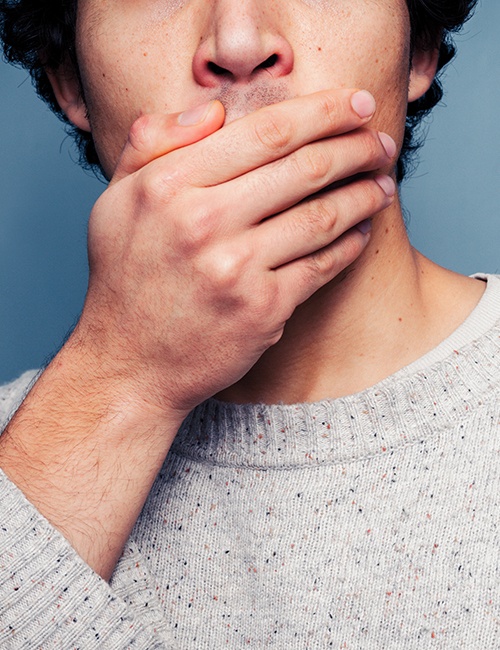 Man in need of sedation dentistry covering his mouth