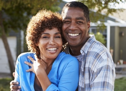 Man and woman smiling after replacing missing teeth