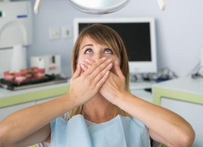 Fearful patient in need of sedation dentistry covering her mouth