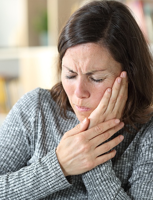 Woman in need of T M J therapy holding her jaw