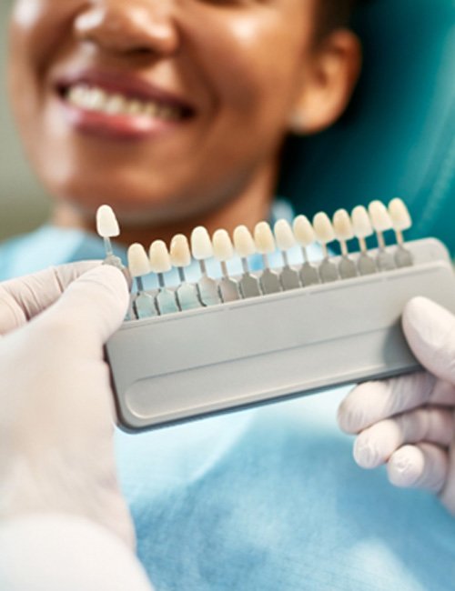 Patient smiling while dentist selects shade of veneer