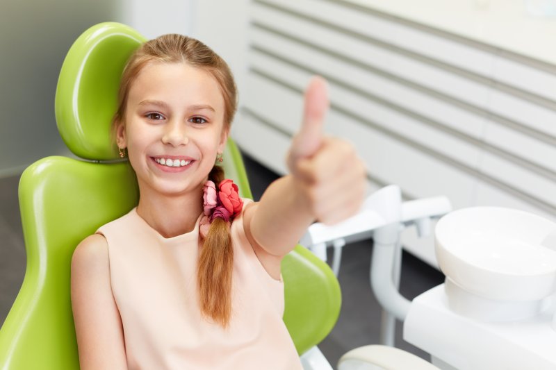 Young girl giving a thumbs up at dentist's office