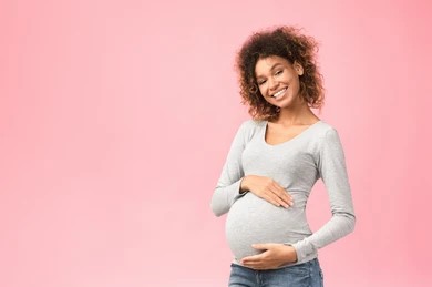 pregnant person smiling on pink background