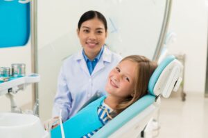 Happy child posing with her dentist in treatment room 