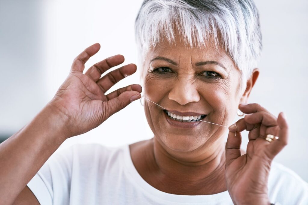 An older woman flossing her teeth