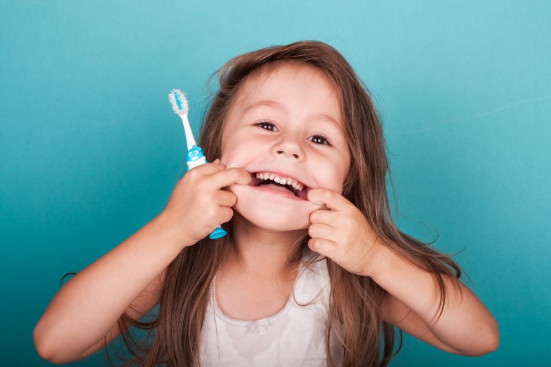 Child makes silly face with toothbrush